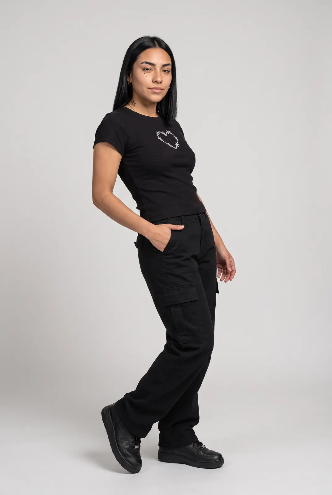 Nova Reyes wearing the BARBED Baby Tee in Black, three quarter lean