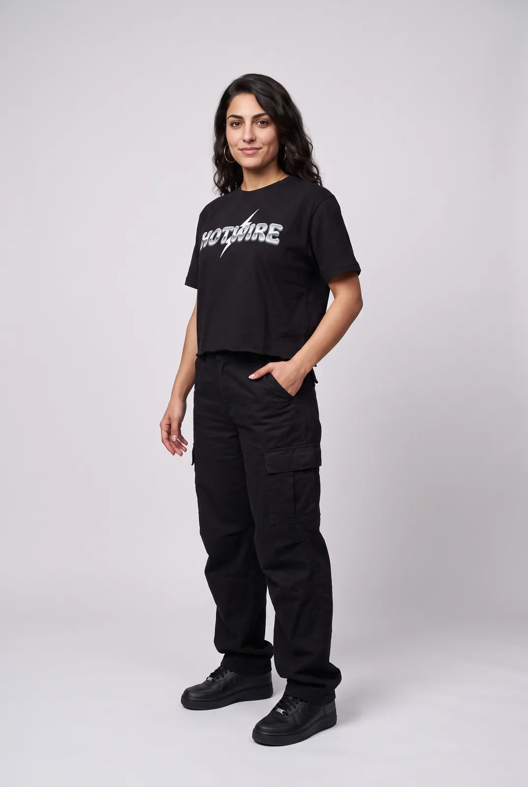 Amara Haddad wearing the HOTWIRE Cropped Tee in Black, three quarter lean